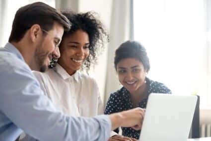 training employees sitting at a laptop conversing.