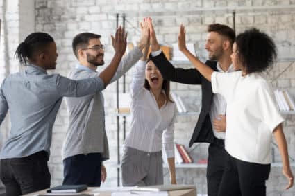 Excited successful multiracial business people giving high five, celebrating win.