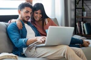 Why Online Reputation Management Matters In Multifamily Happy beautiful couple using computer while sitting on the couch at home.