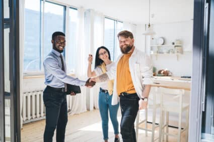 AI Impact on Multifamily Black realtor and happy couple sealing deal by shaking hands