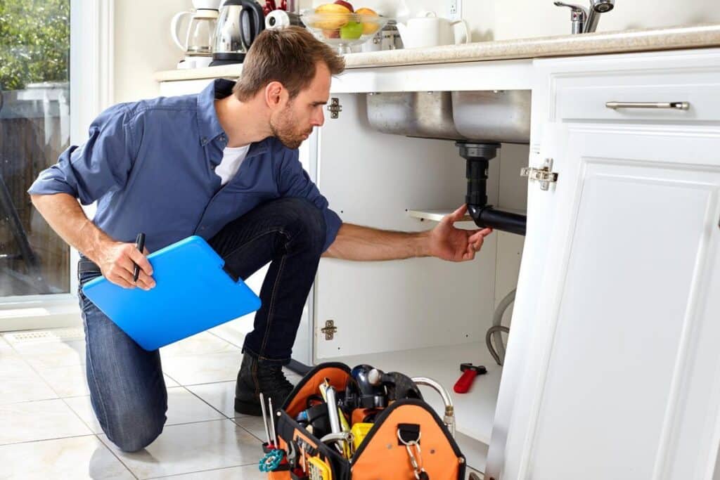 maintenance man inspecting sink in resident's apartment