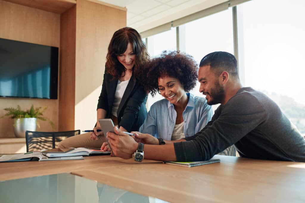 group of diverse property leasing employees smiling at a tablet, taking an employee survey