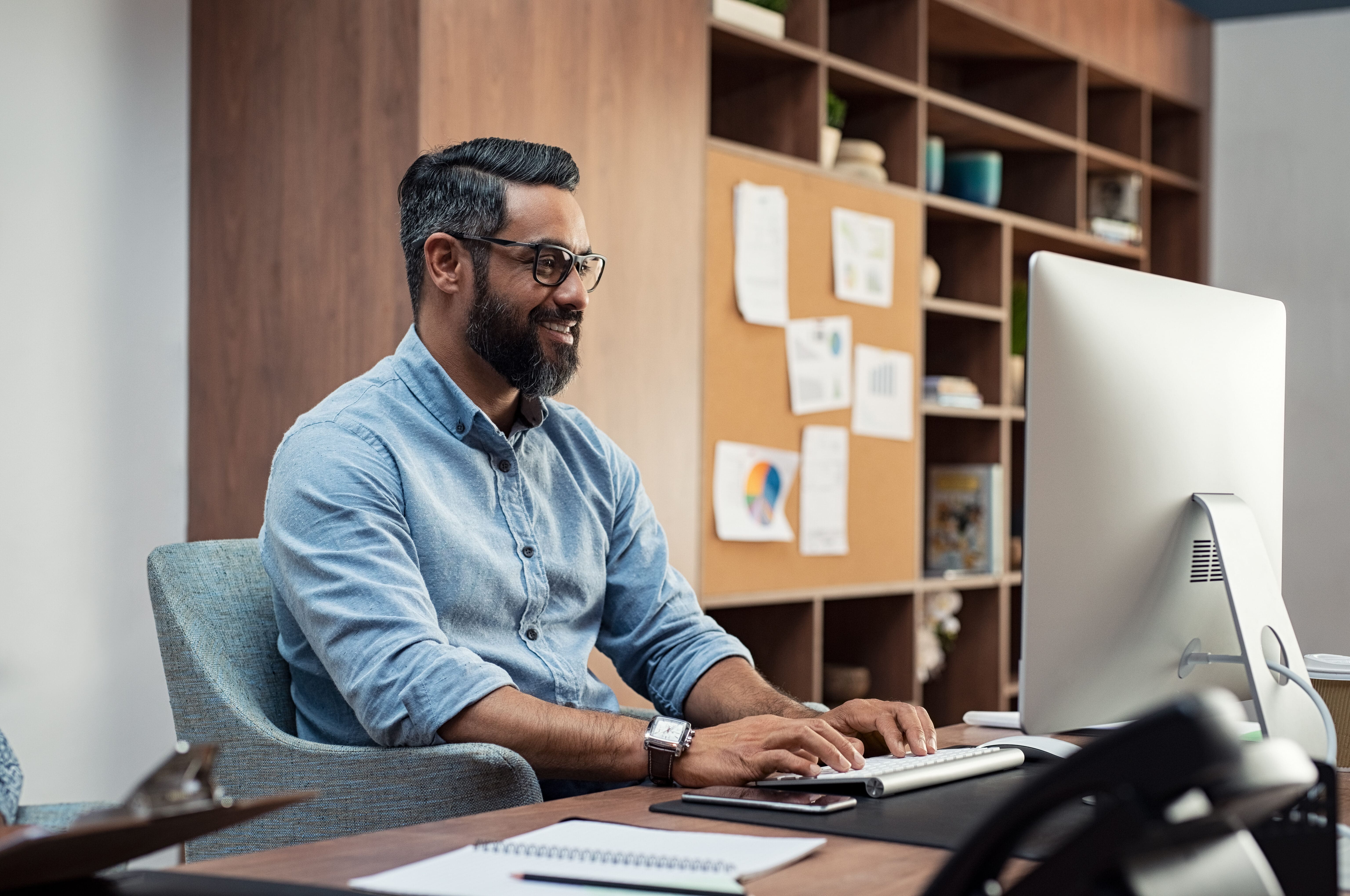 multifamily training director man, smiling and staring at computer screen