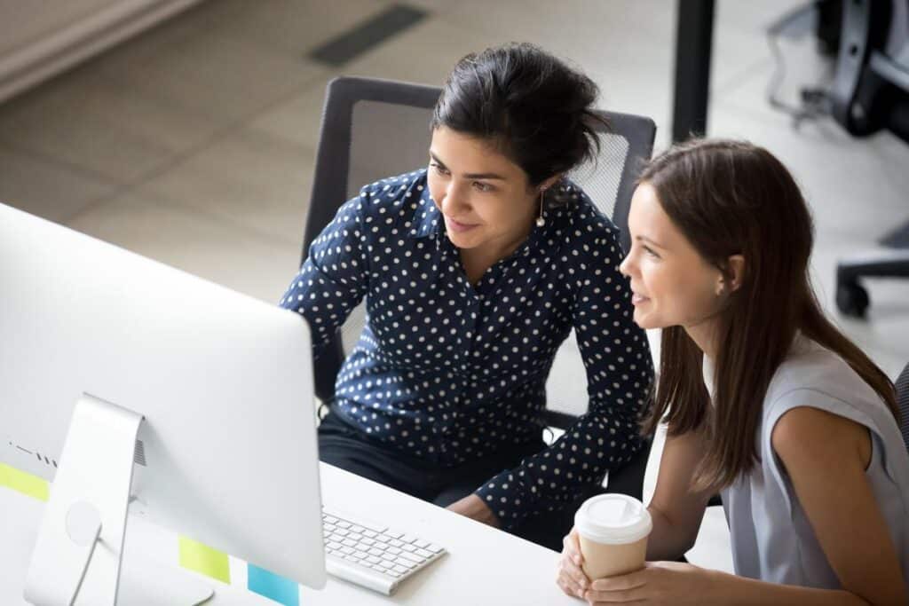 Multiracial colleagues sitting together looking at laptop