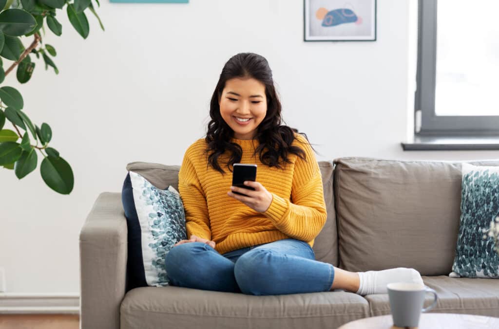 multifamily marketing woman, happy asian checking google reviews on smartphone at home