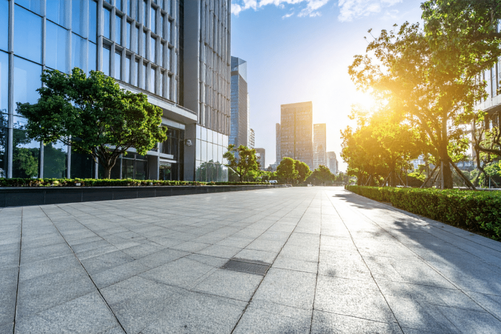 Modern commercial office buildings with landscaped walkway and sunlight, representing sustainable real estate and ESG-focused property environments.