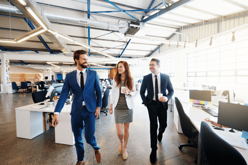 Three professionals walking and talking together in a modern open-plan commercial office space