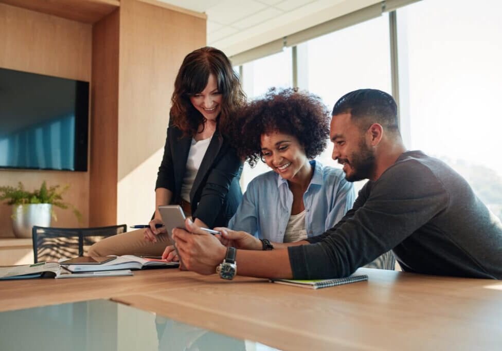 group of diverse property leasing employees smiling at a tablet, taking an employee survey