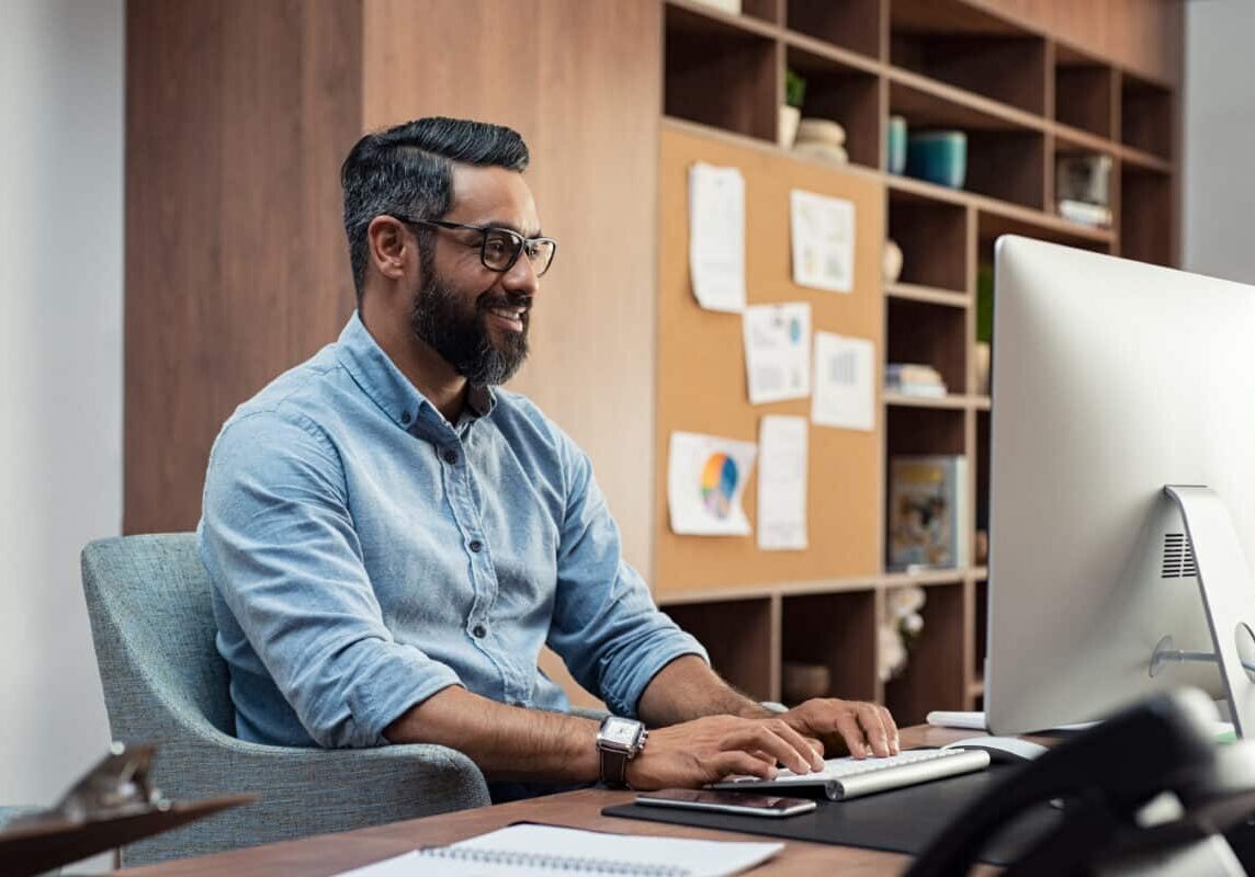 multifamily training director man, smiling and staring at computer screen