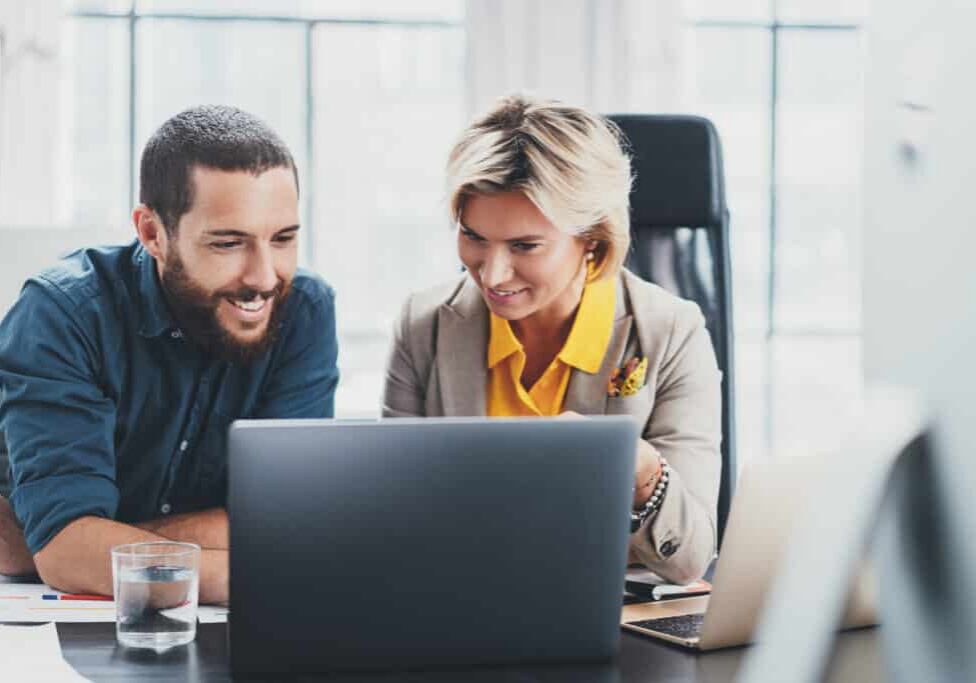 director of training woman and learner man smiling at computer