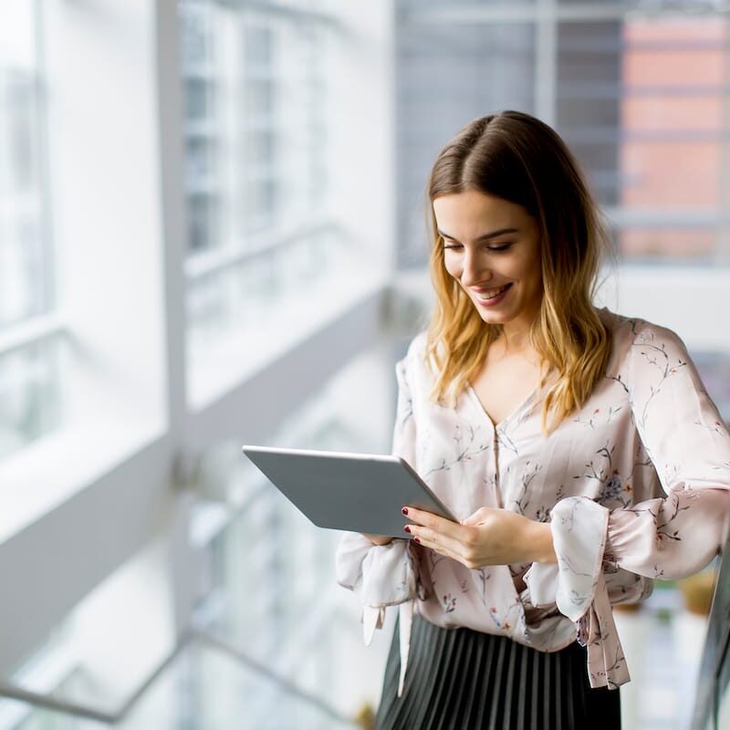 Attractive businesswoman using a digital tablet to complete tenant survey while standing on the stairs in the office
