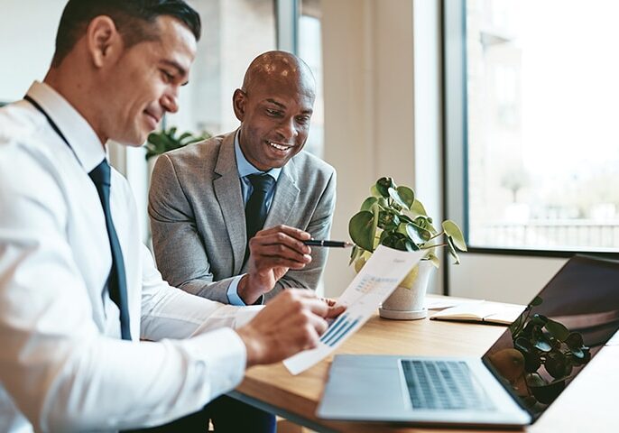 Two diverse businessmen going over graphs together in an office