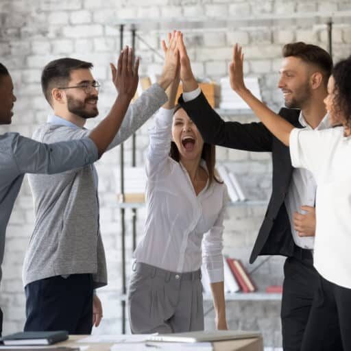 Excited successful multiracial business people giving high five, celebrating win. Good teamwork result concept. Happy employees team engaged in team building activity at corporate meeting.