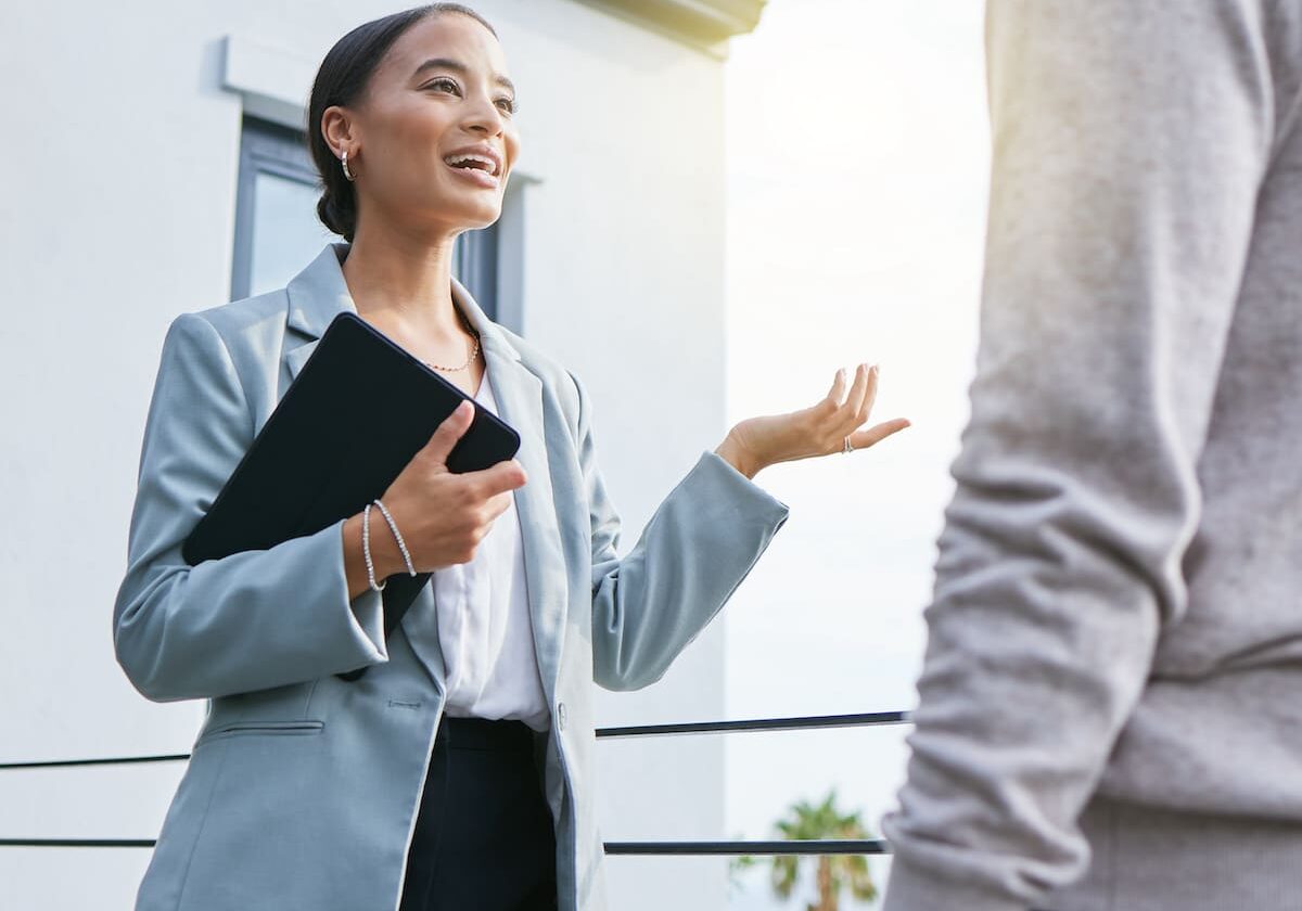 Shot of a young female real estate agent showing a client a house.