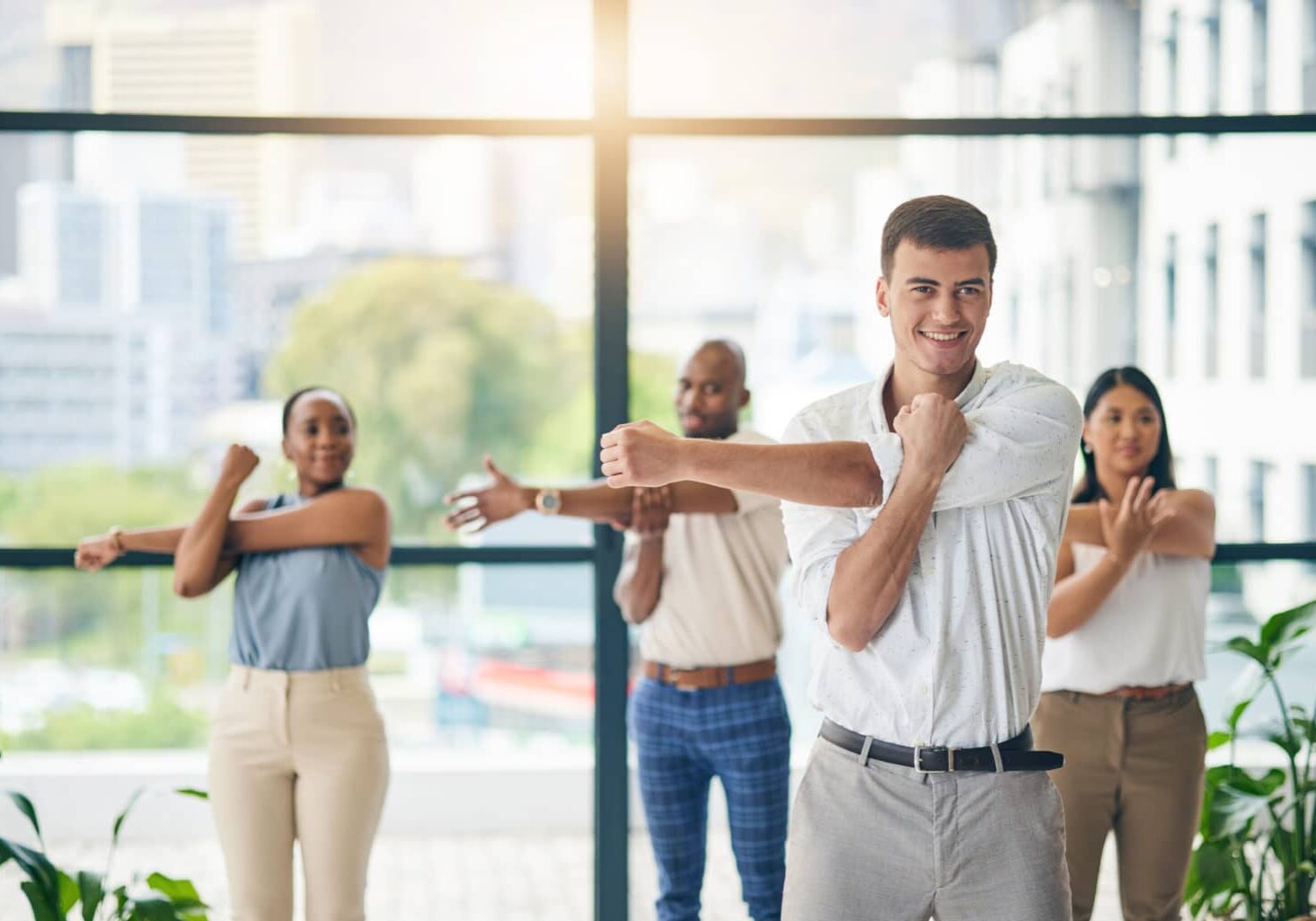 Workout, stretching and a group of business people in the office to exercise for health or mobility together. Fitness, wellness and coach training an employee team in the workplace for a warm up.