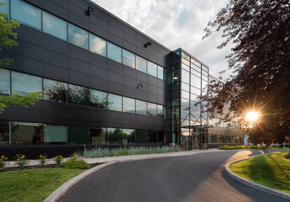 Exterior of a modern commercial office building with glass facade and landscaped grounds at sunset