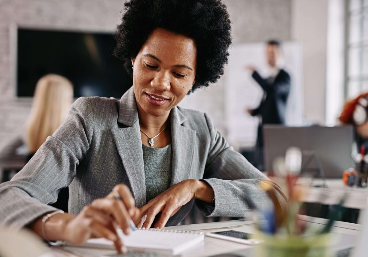 Smiling black entrepreneur working on financial reports at her desk in the office.