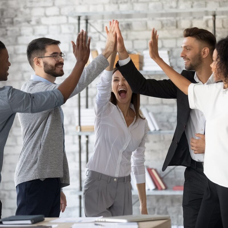 Excited successful multiracial business people giving high five, celebrating win.