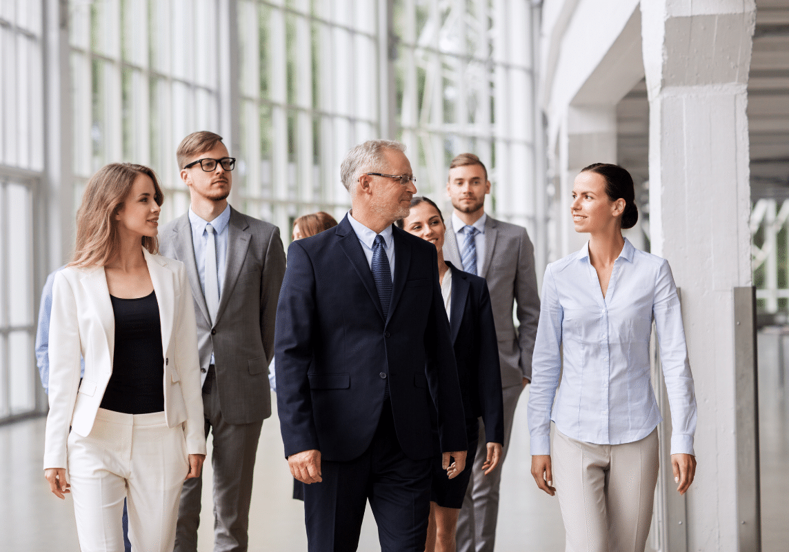 Group of business professionals walking together through a bright commercial office building corridor