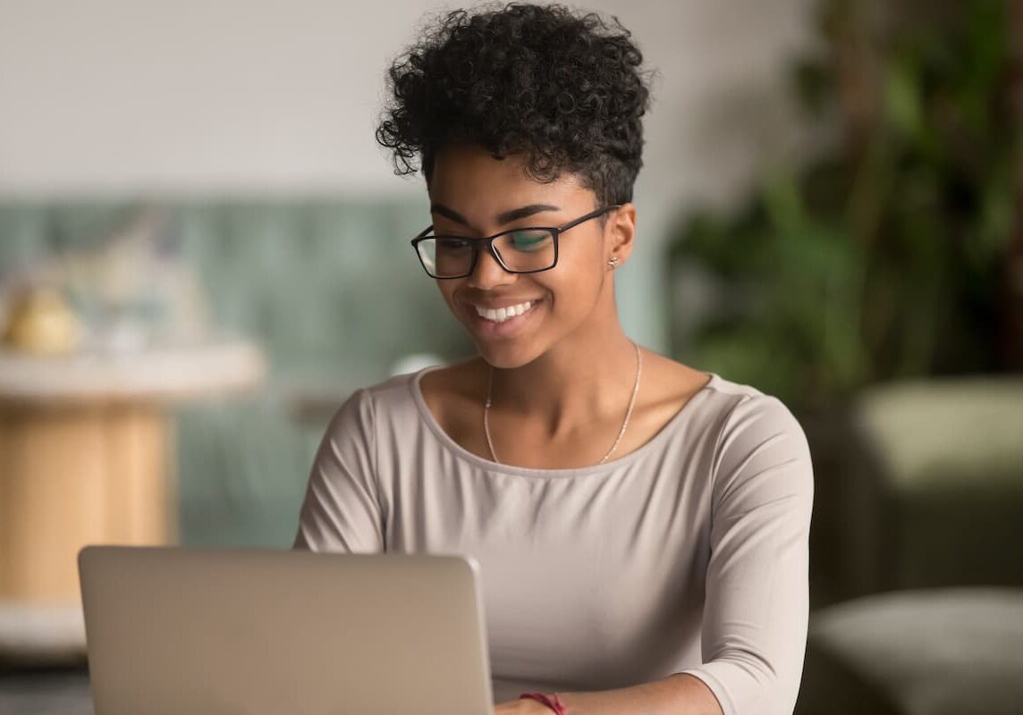 Happy, smiling african american woman property manager taking grace hill sparks microlearning courses on laptop